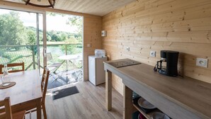 A wooden interior with a dining table, chairs, a coffee machine, and a refrigerator. - Camping Les Castors - Cabanes Insolites (Burnhaupt-le-Haut)