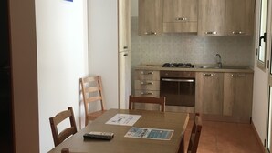 A compact kitchen with wooden cabinets, a gas stove, and a sink. - Residence Alba (Vieste)