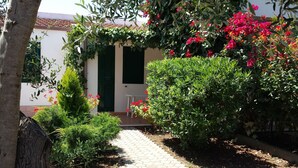 A garden pathway leading to a building with a tiled roof and green shutters. - Residence Alba (Vieste)