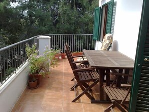 A balcony with a wooden table and chairs, surrounded by potted plants and a metal railing. - Residence Alba (Vieste)