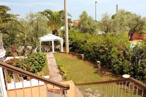 A garden with a white gazebo, a paved pathway, and various plants. - Residence Alba (Vieste)
