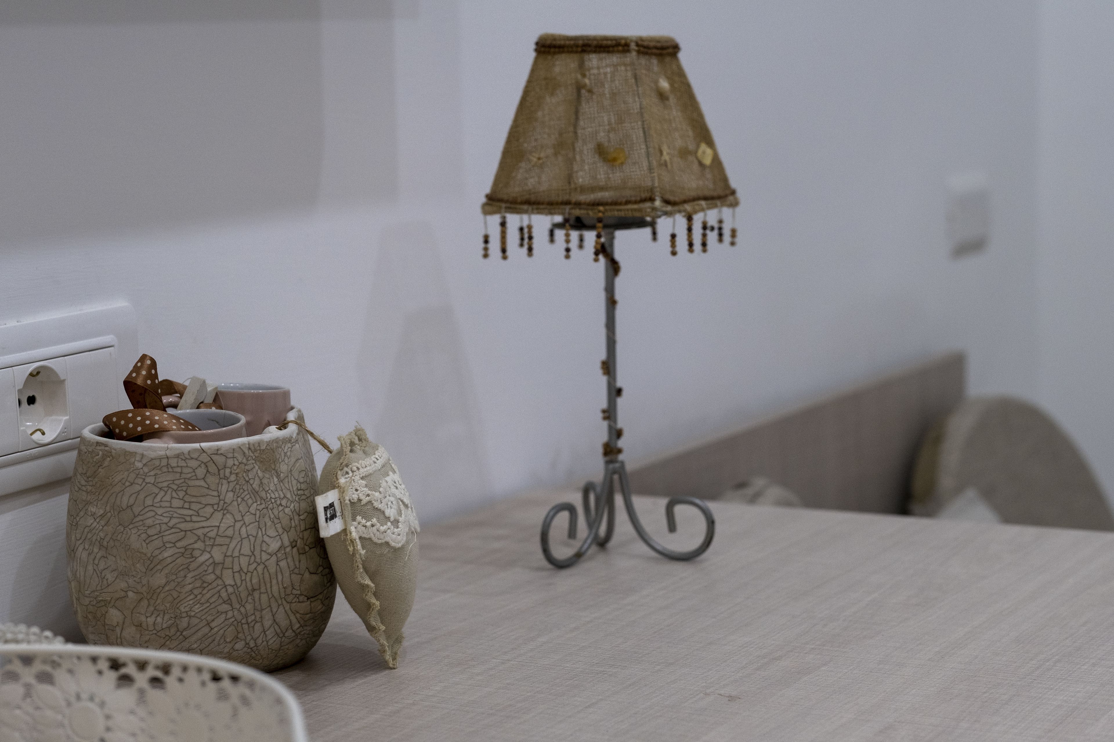 A table with a lamp, a ceramic pot, and a lace item.