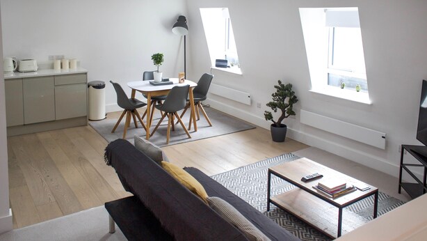 A modern apartment with a dining area, a living room with a sofa, a coffee table, and a TV. - Cosy Two Bed in Islington (London)
