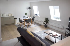 A modern apartment with a dining area, a living room with a sofa, a coffee table, and a TV. - Cosy Two Bed in Islington (London)