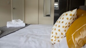 A neatly made bed with white linens, a folded towel, and a pillow with a polka dot pattern. - Cosy Two Bed in Islington (London)