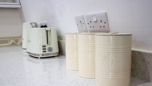 A kitchen counter with a toaster and three beige containers. - Cosy Two Bed in Islington (London)