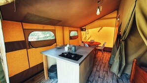 A compact kitchen with a central island, a dining area with a table and chairs, and a window providing a view of the outdoors. - Camping des vignes (Dun)