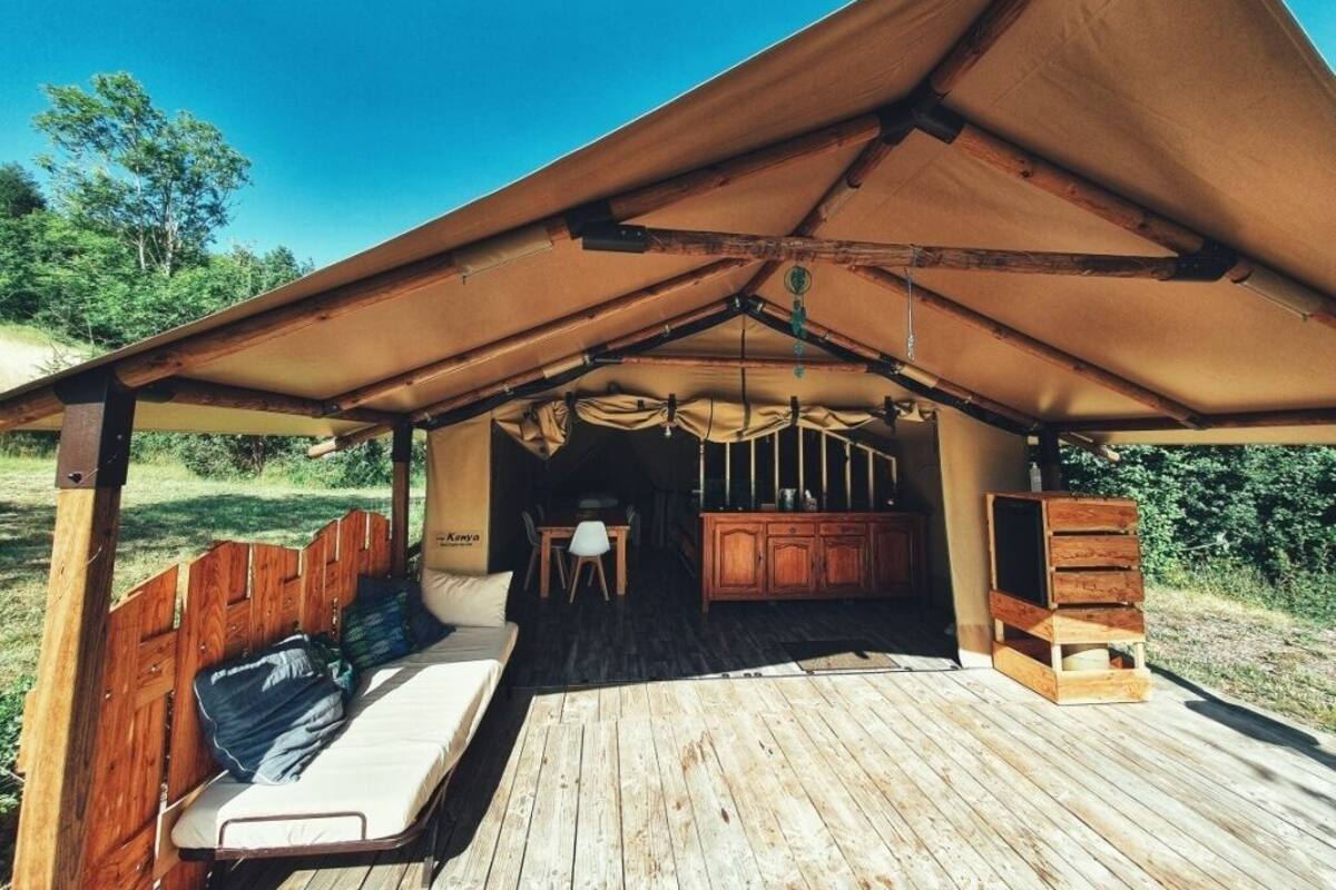 Una terraza de madera con un área de descanso cubierta, una mesita y un armario.