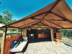 A wooden deck with a covered seating area, a small table, and a cabinet. - Camping des vignes (Dun)