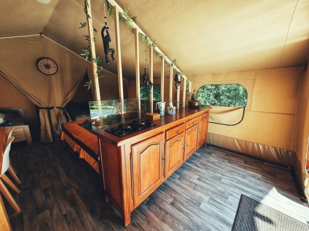 A compact kitchen with wooden cabinets, a central island, and a window overlooking greenery.