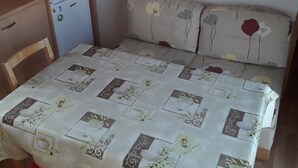Una habitación pequeña con una cama, una mesa, una silla, un microondas y un refrigerador.
