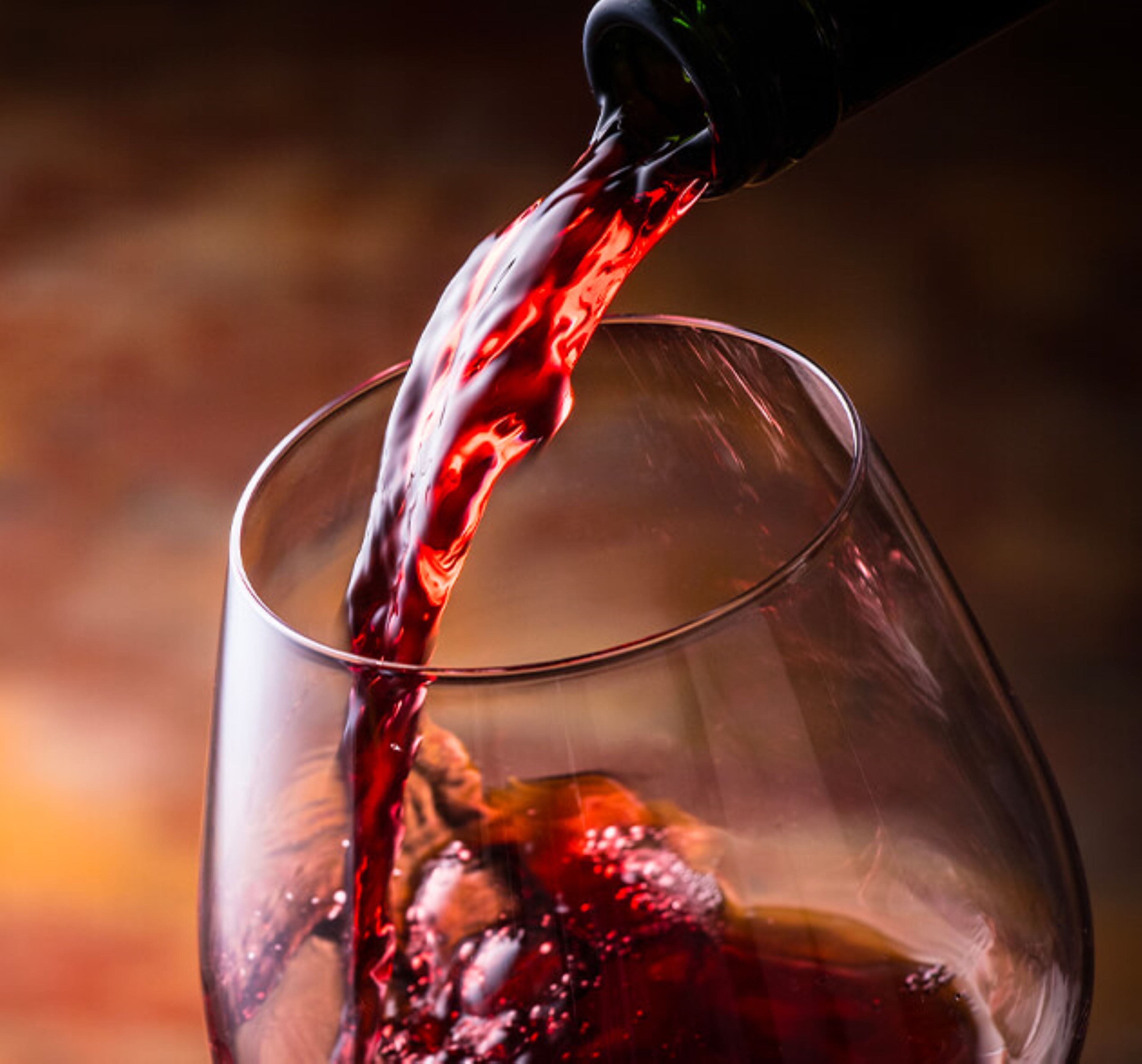 A clear glass of red liquid being poured into it.