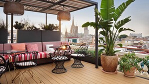 Una terrazza sul tetto con divano, sedie e piante in vaso.