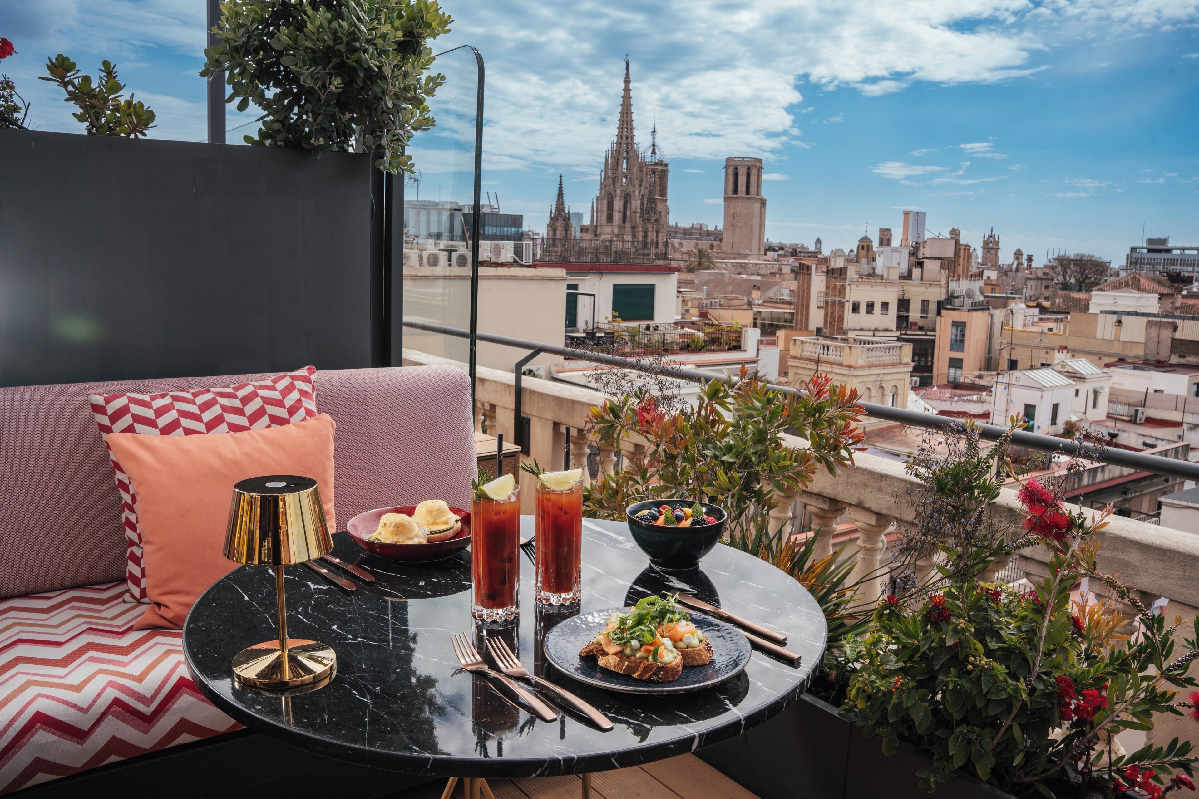 Ein Balkon mit Esstisch, einer Sitzecke und Blick auf eine Stadtlandschaft, darunter ein Dom.