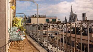 Ein Balkon mit schmiedeeisernen Geländern, einem Korbstuhl und einem Blumentopf.