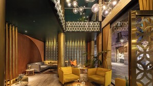A lobby with a modern design, featuring a sofa, armchairs, and a coffee table. There is a patterned wall and a decorative ceiling light fixture. - Kimpton Vividora Hotel by IHG (Barcelona)