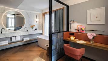 A modern bathroom with a marble vanity, a freestanding bathtub, and a separate shower area.