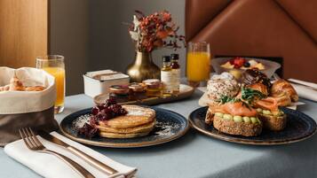 Ein Frühstücksbuffet mit Gebäck, Sandwiches und einer Obstschale auf einem Tisch.