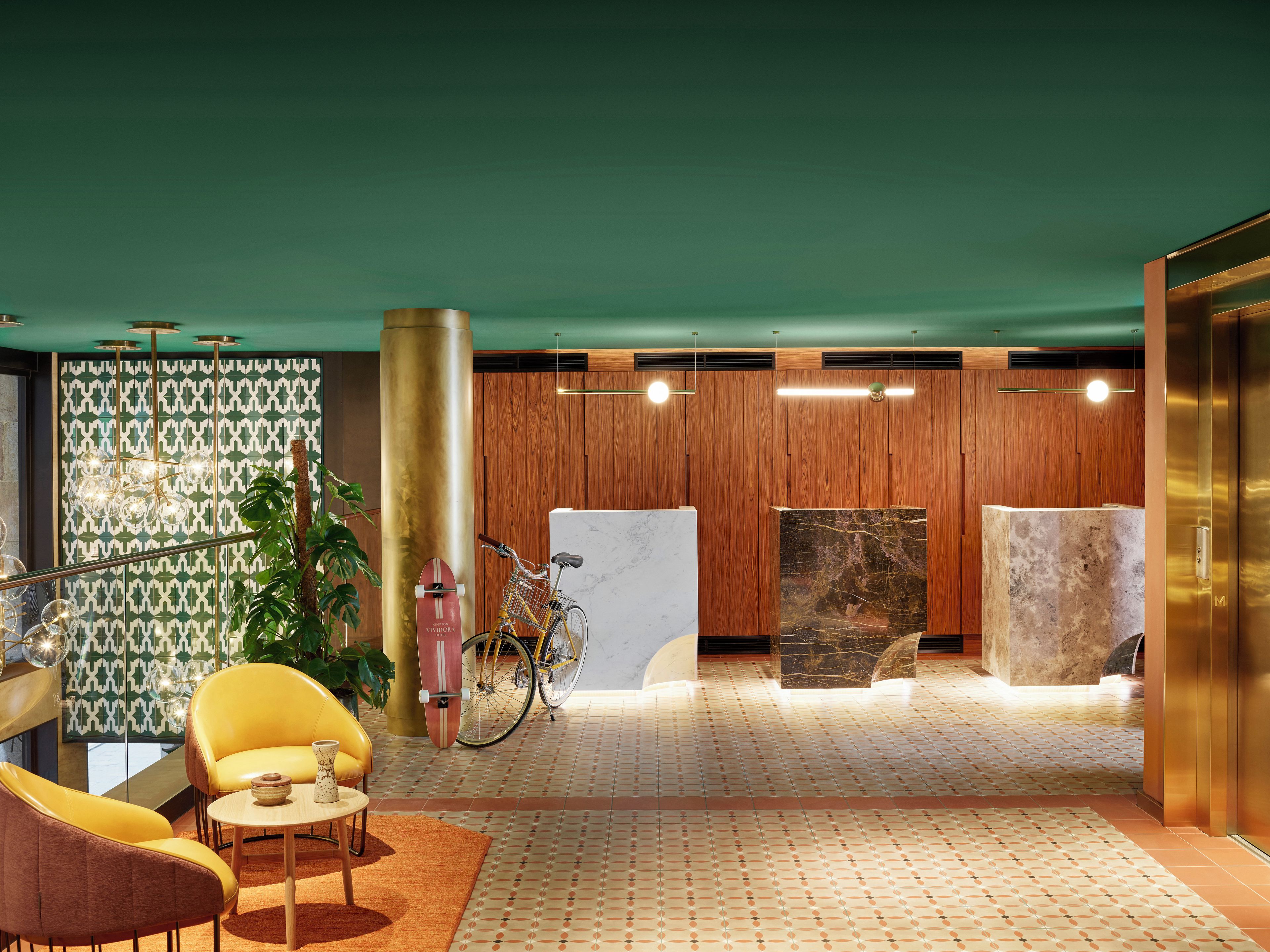 A lobby with a reception desk, wooden panel walls, a bicycle, and a plant.