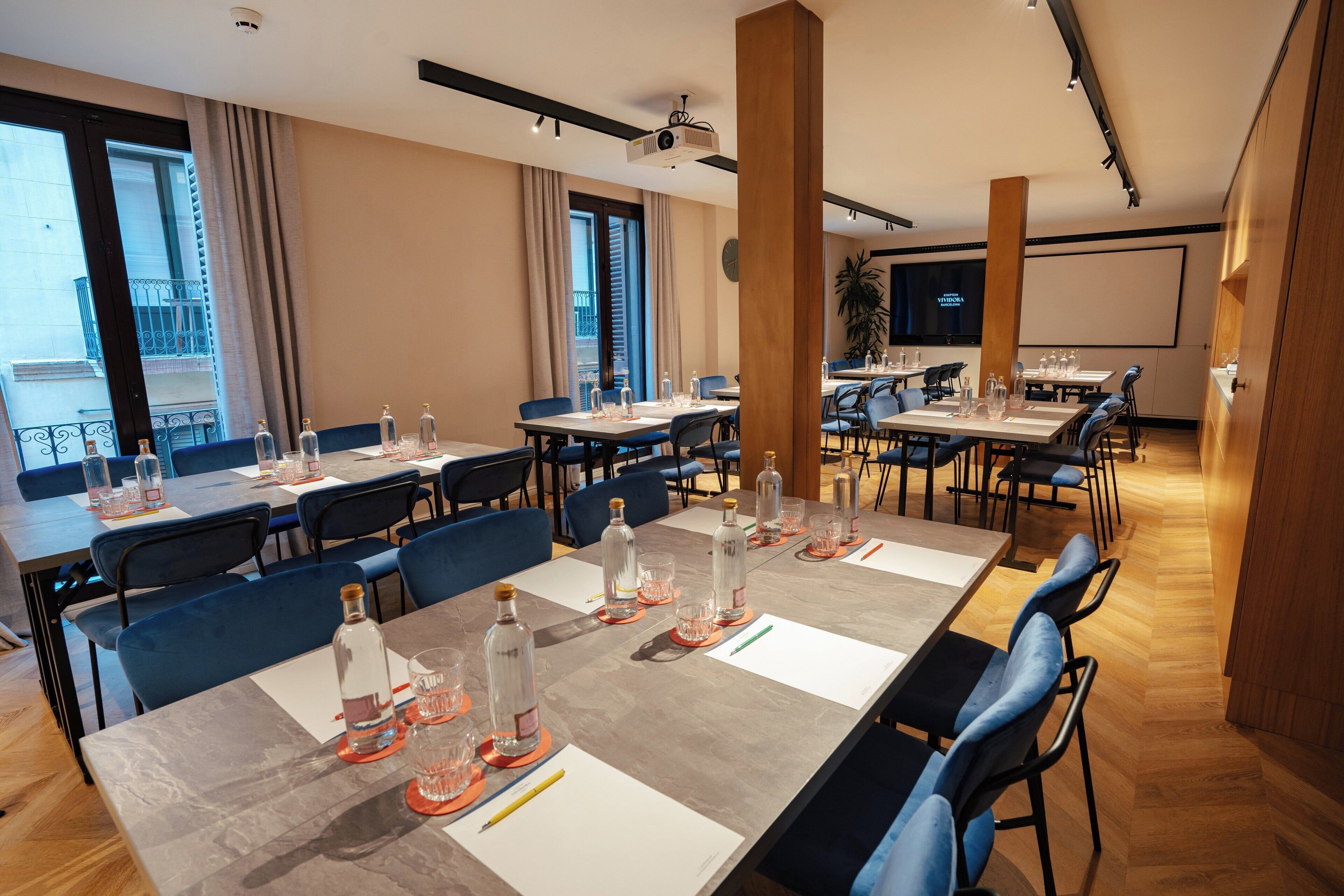 A conference room with multiple tables, chairs, and a projector screen.