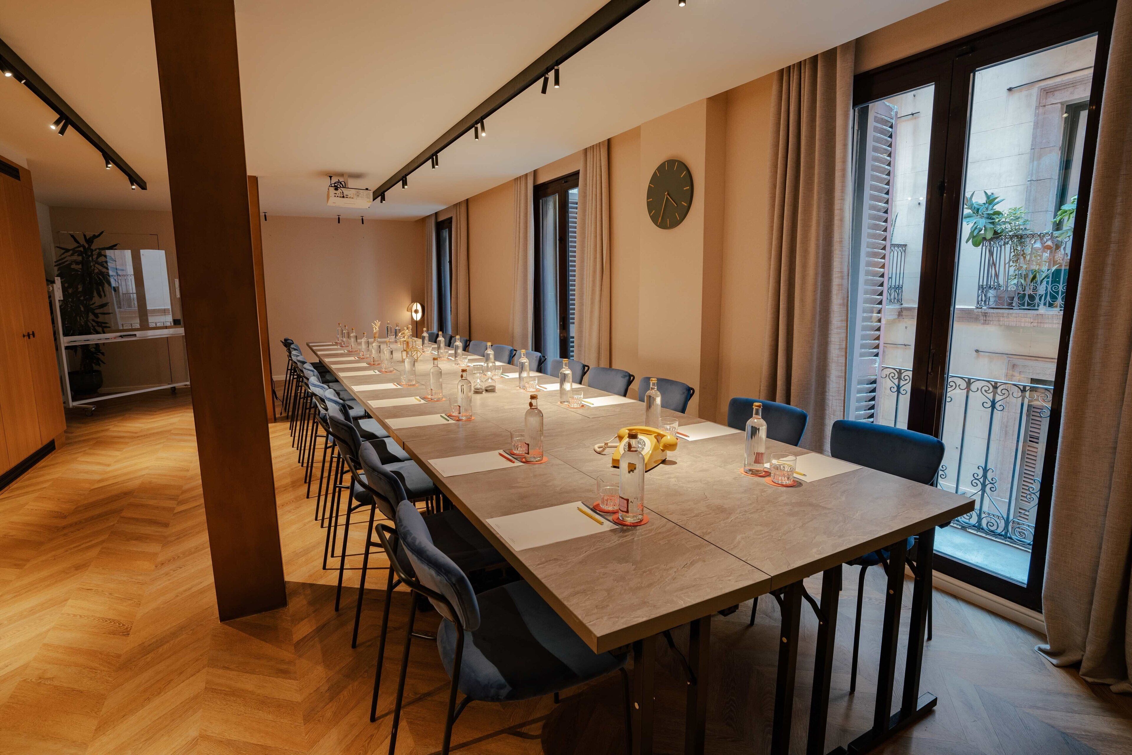 Une salle de conférence avec une longue table, des chaises et une horloge au mur.