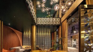 A modern lobby with a sofa, armchairs, a coffee table, and decorative lighting. - Kimpton Vividora Hotel by IHG (Barcelona)