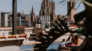 A rooftop terrace with a view of a historic cathedral and modern buildings. - Kimpton Vividora Hotel by IHG (Barcelona)