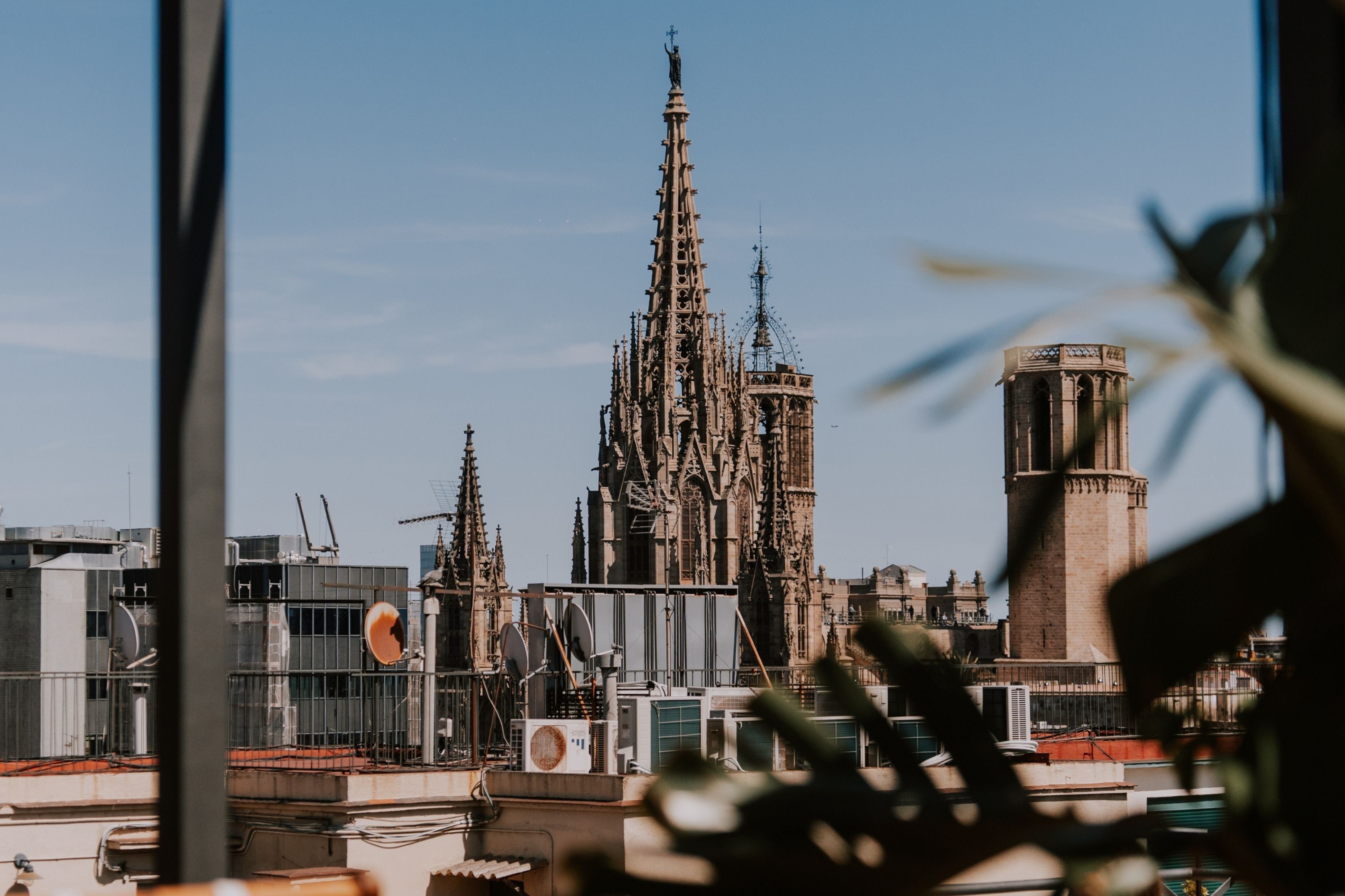 Een gotische kathedraal met gedetailleerde architectuur, een klokkentoren en een modern gebouw met schotels op de voorgrond.