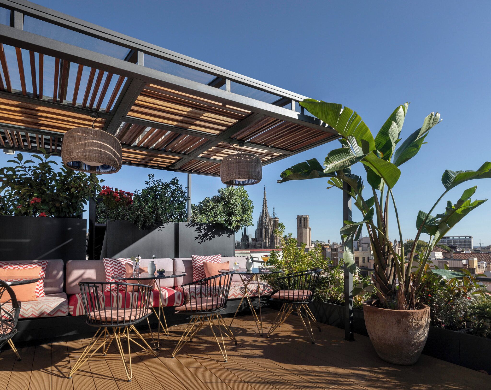 An outdoor seating area with a pergola, cushioned seating, and potted plants.