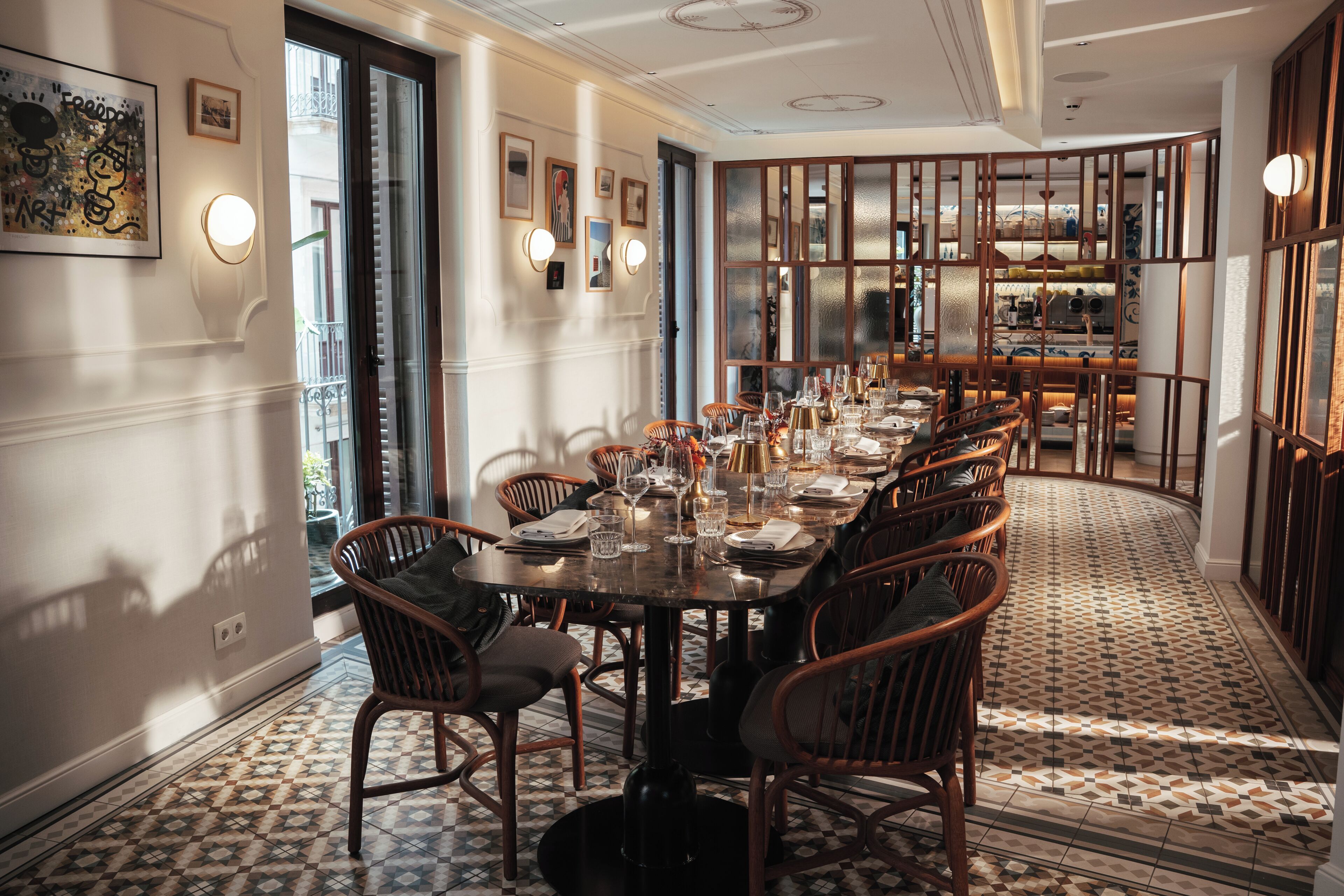 A dining area with a long table set for multiple guests, surrounded by wicker chairs.
