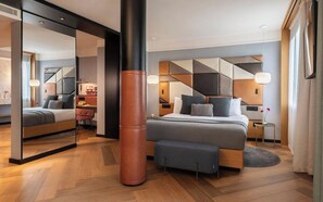 A modern hotel room with a large bed, a sitting area, a mirror, and a large pillar. - Kimpton Vividora Hotel by IHG (Barcelona)