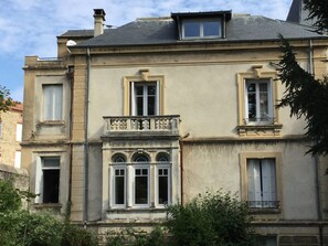 Un immeuble de deux étages doté d’un balcon, de nombreuses fenêtres et d’une cheminée.