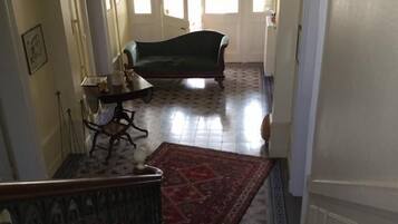 Una escalera conduce a una sala de estar con un sofá verde, un tapete estampado y una araña.