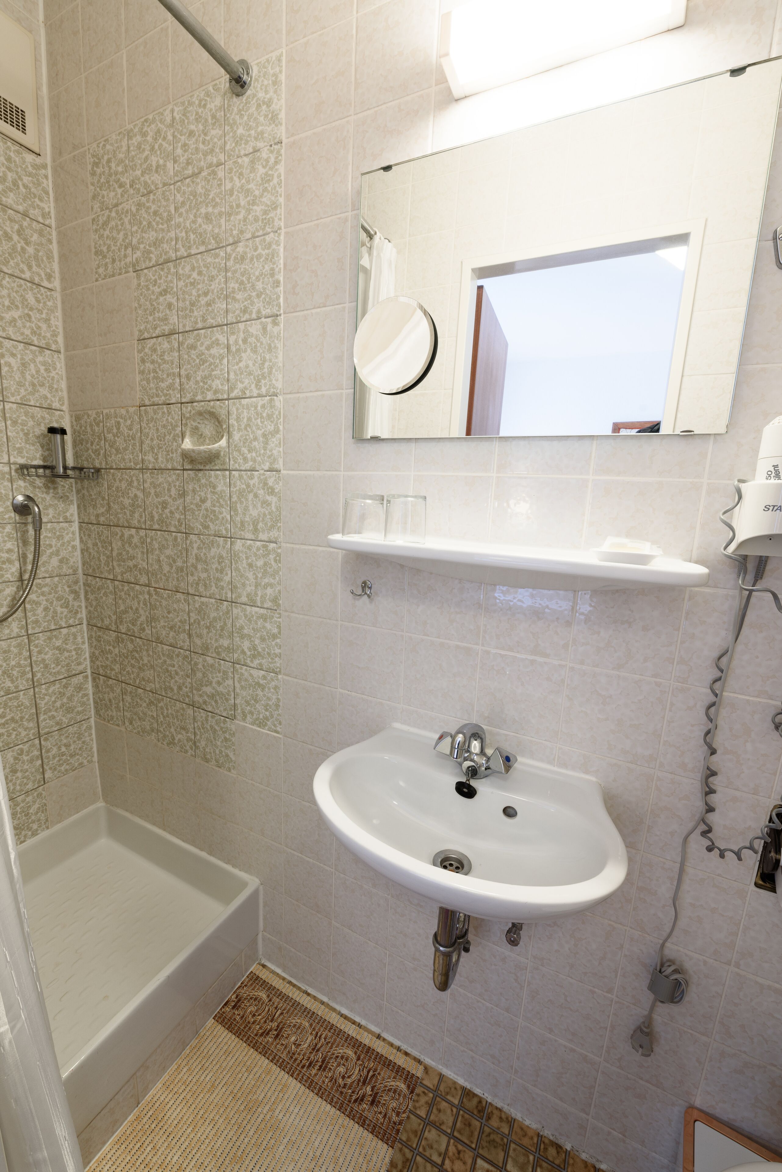 Une salle de bain avec une douche, un lavabo et un miroir.