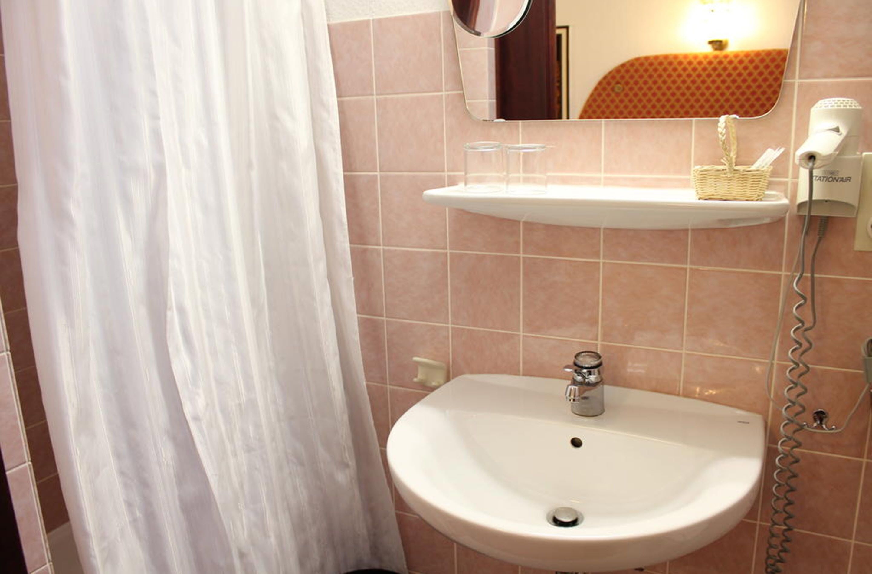 Een badkamer met een witte wastafel, een spiegel, een handdoekhouder en een douchegordijn.