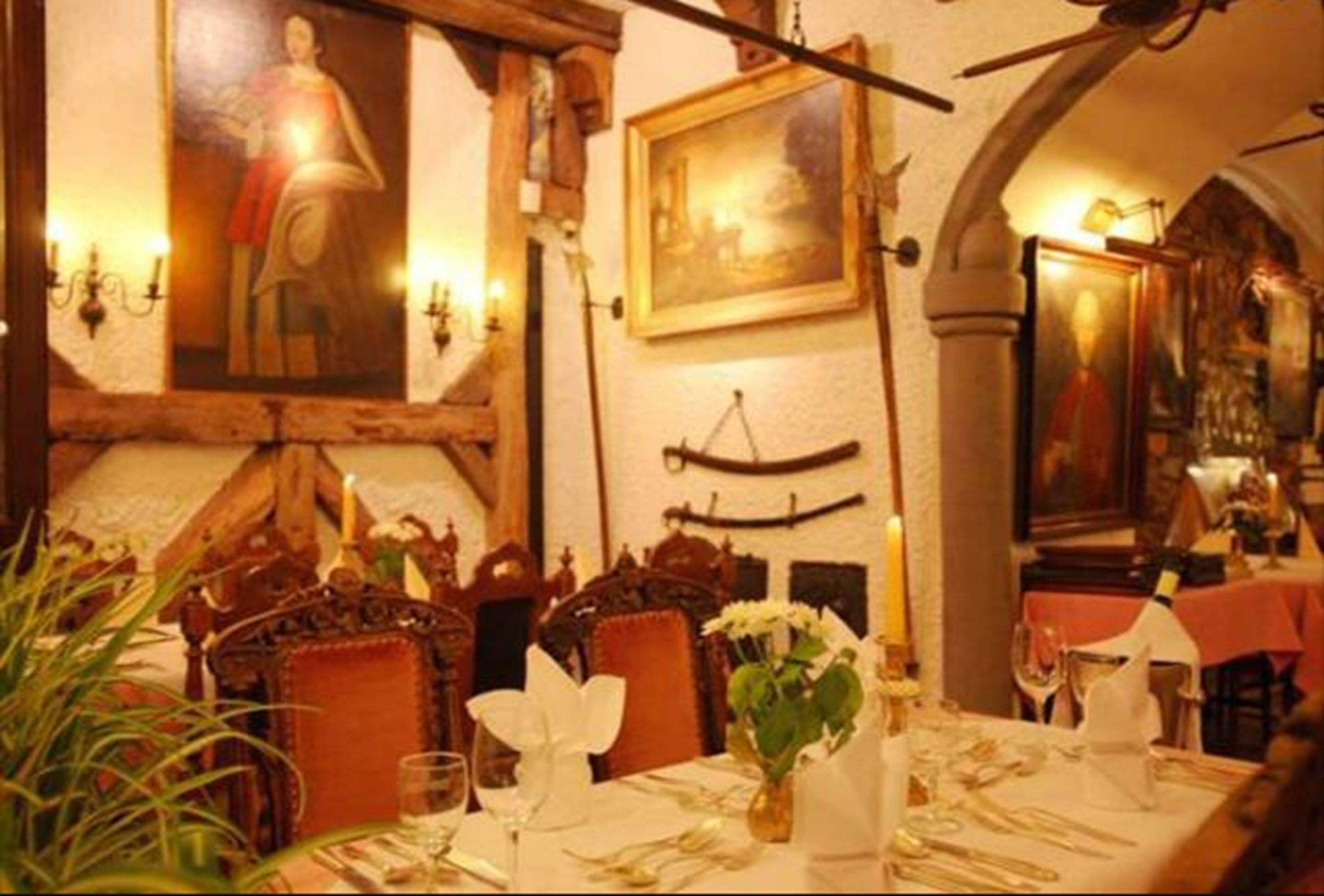 Un comedor con una mesa dispuesta para dos personas, que incluye un jarrón con flores, velas y un cuadro en la pared.