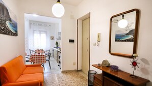 A living room with a sofa, a table with a checkered tablecloth, a wooden cabinet, and a framed picture on the wall. - A Casa di Frà B&B (Palermo)