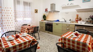 A compact kitchen with a dining area, featuring a checkered tablecloth, a stove, and a sink. - A Casa di Frà B&B (Palermo)
