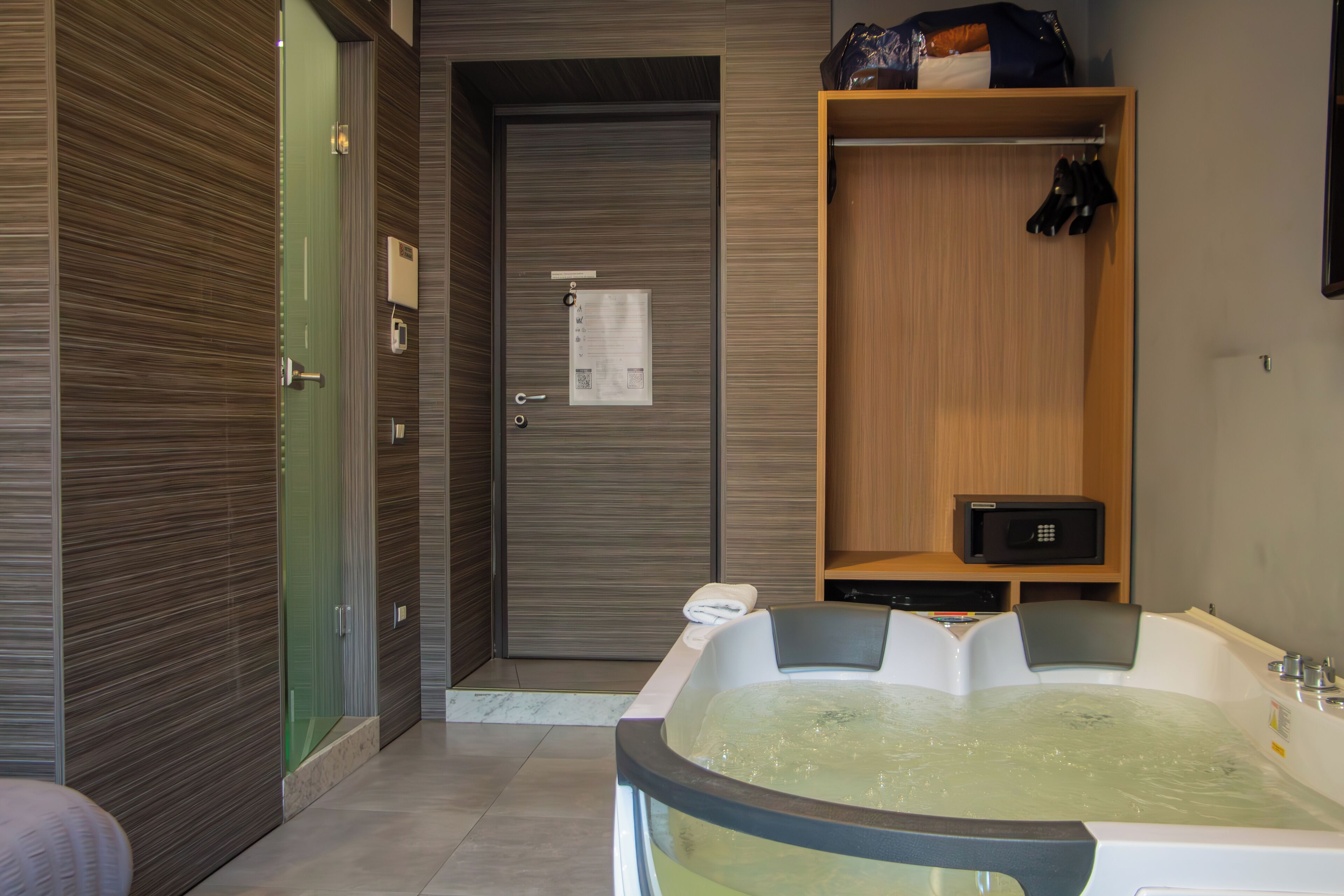 A modern bathroom with a large bathtub, a wooden wardrobe, and a glass shower enclosure.