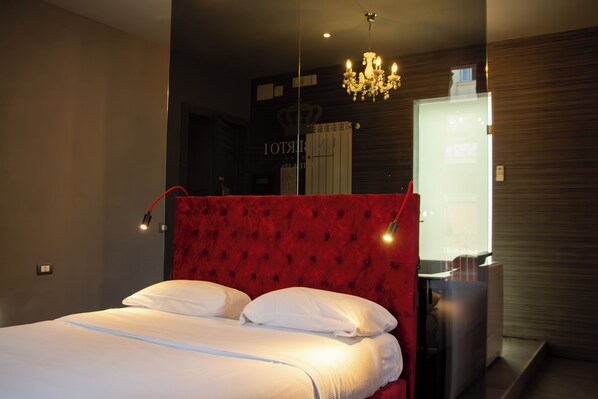 A modern bedroom with a red upholstered headboard, a bedside table, and a large mirror. - Umberto Primo Suite e Spa (Naples)