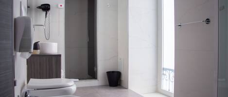 A modern bathroom with a toilet, bidet, and a shower area.