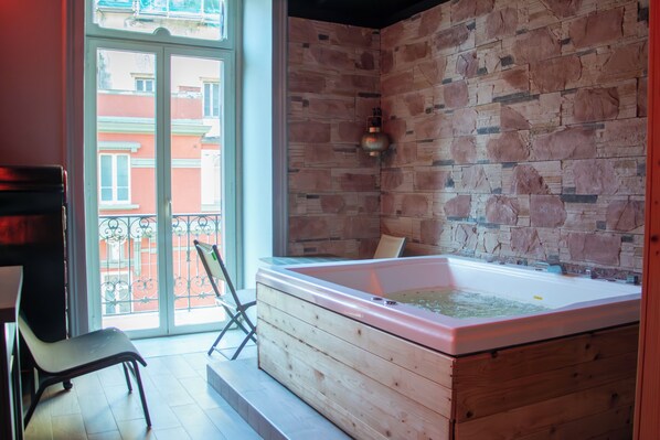 A room with a wooden bathtub, a chair, and a view of the outside through a glass door. - Umberto Primo Suite e Spa (Naples)