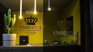 A reception desk with a potted plant, a sign for Wi-Fi, and a framed picture on the wall. - Umberto Primo Suite e Spa (Naples)