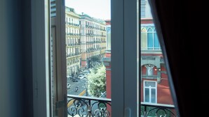 A view from a window with a balcony, featuring a street with buildings and a clear sky. - Umberto Primo Suite e Spa (Naples)