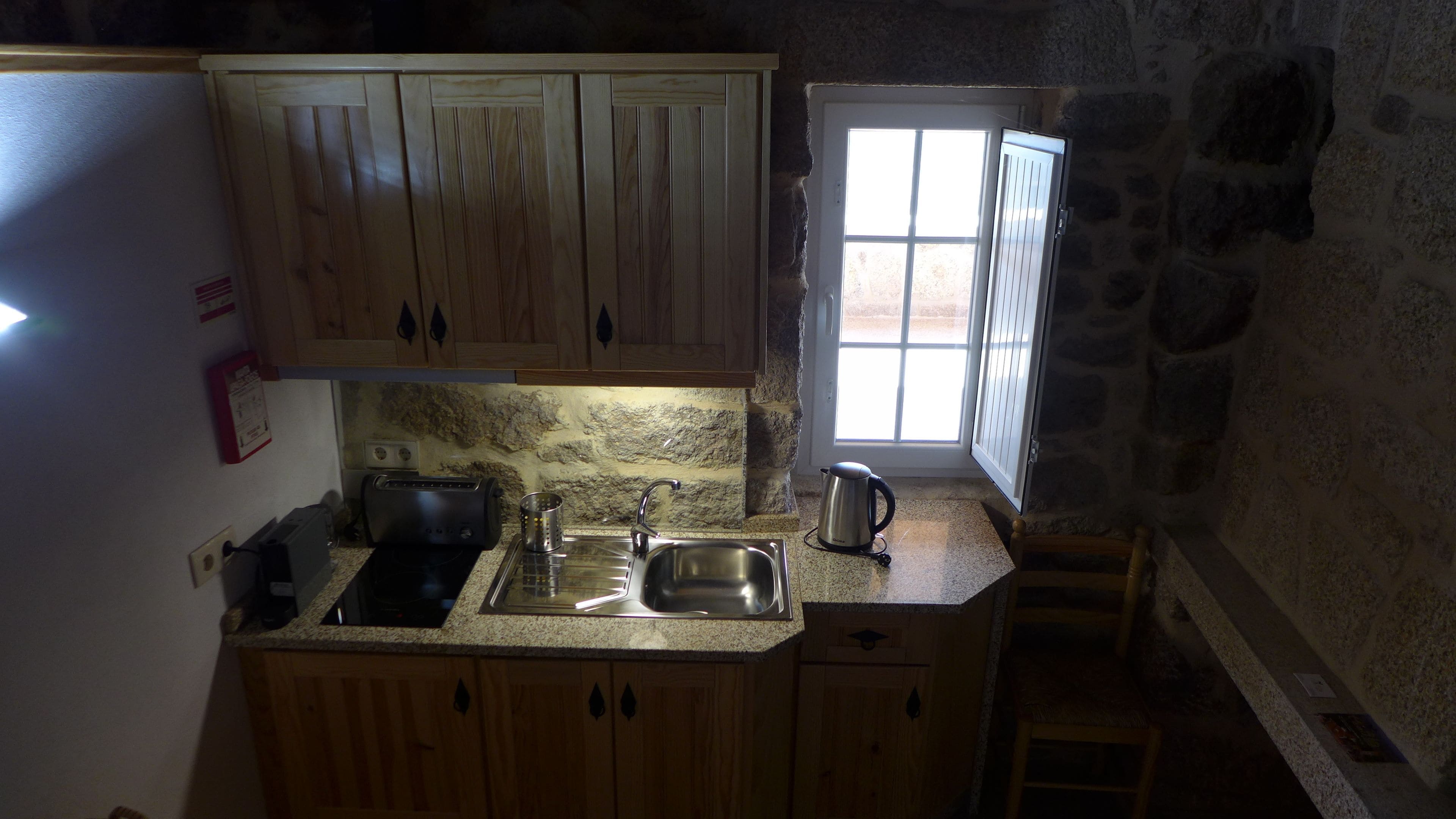 A small kitchen with wooden cabinets, a sink, a toaster, and a kettle.