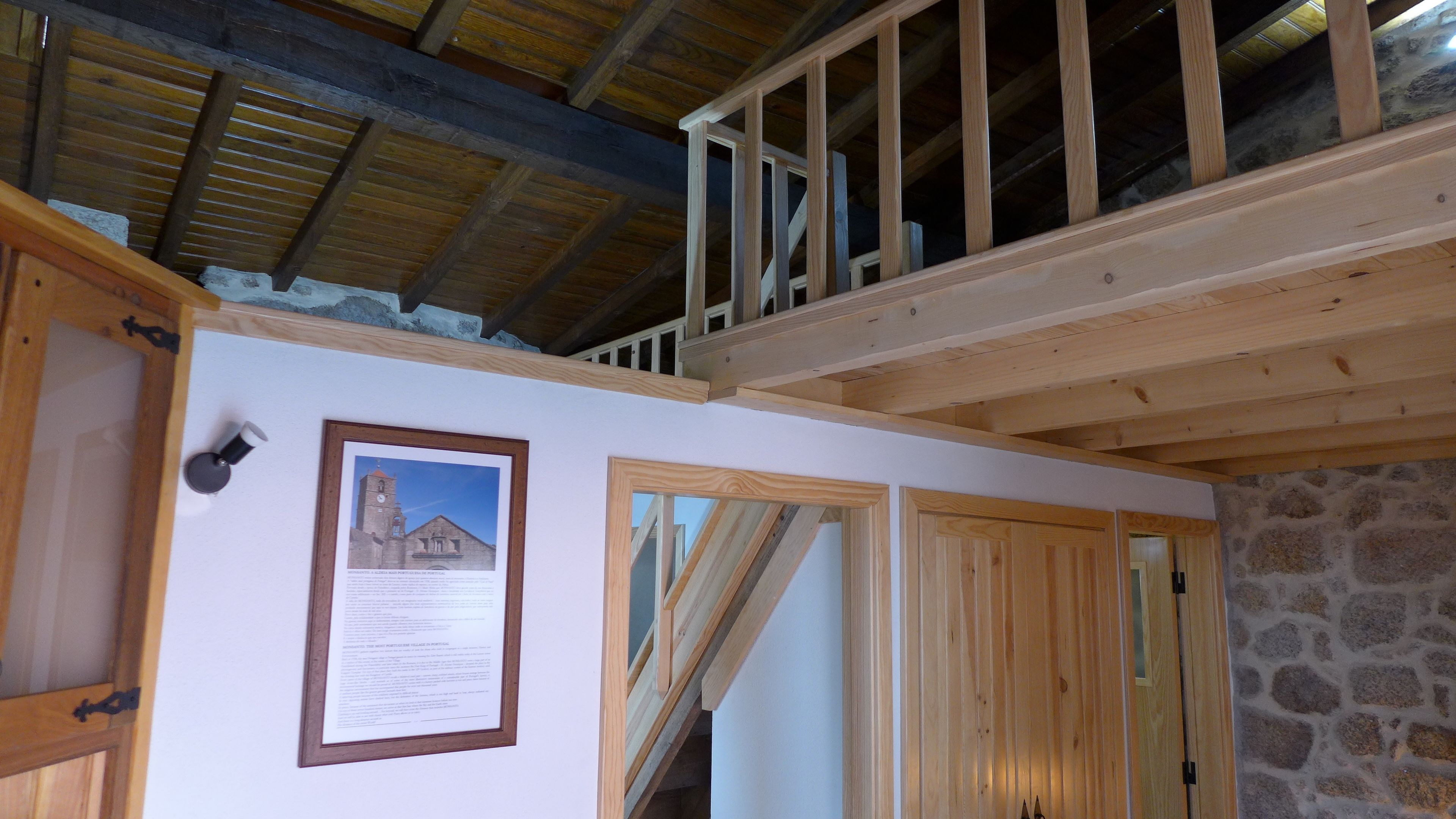 A room with a wooden staircase, a framed informational poster, and a stone wall.