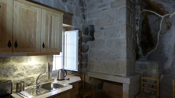 Eine Küche mit Holzausstattung, einer Steinwand, einem Fenster und einem Spülbecken.