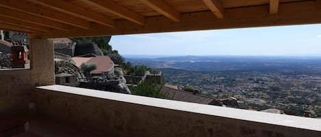 Un balcon en pierre avec un plafond en bois donnant sur une vallée.