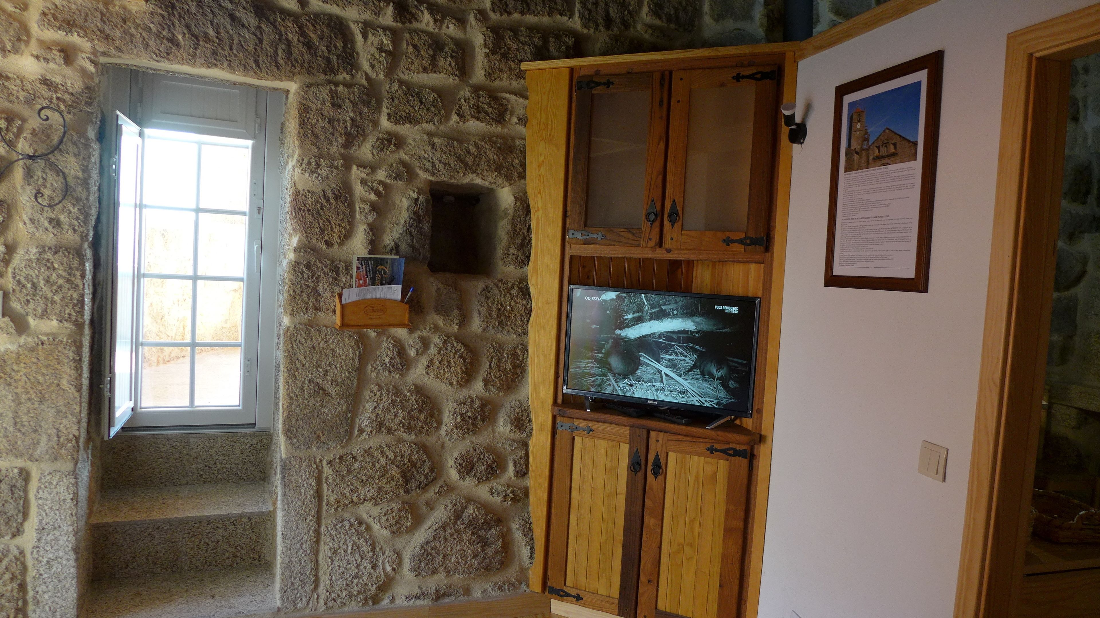 Una habitación con paredes de piedra, un armario de madera y un televisor.