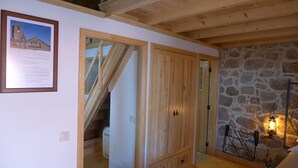 Una habitación con techo de madera, pared de piedra y un cuadro enmarcado en la pared.